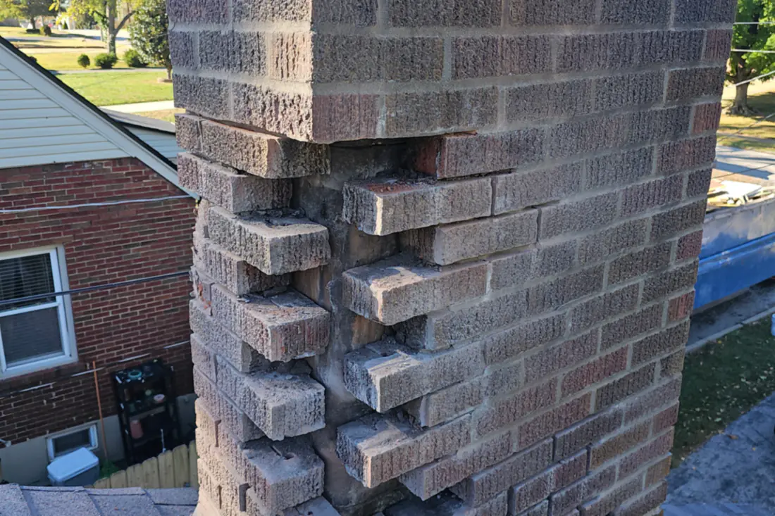 The corner of a chimney where the mortar has gone: corbel bricks stepped out of line and crumbling away.