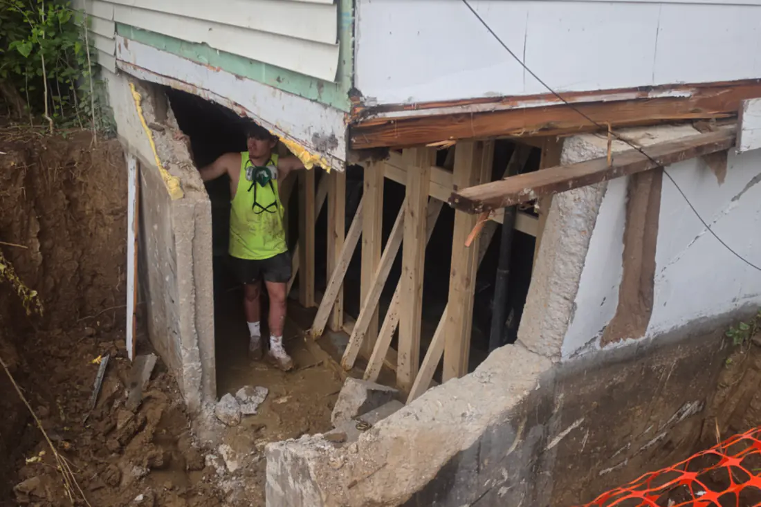 The corner of a house carried on timber cribbing while the foundation under it is opened up.