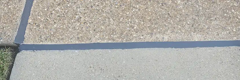An exposed aggregate slab meeting a smooth finished walk at a tooled joint.
