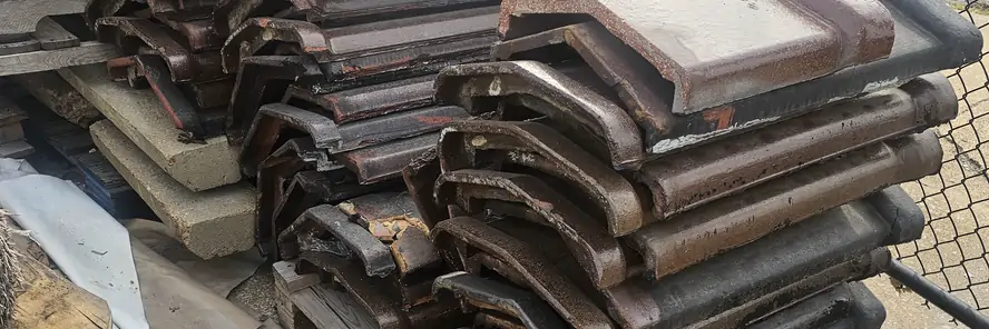 Old clay chimney caps and coping taken off a job and stacked on a pallet.