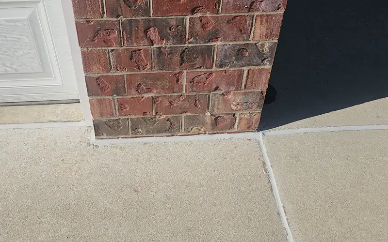 Concrete run up to the garage door and butted clean against the brick pier.