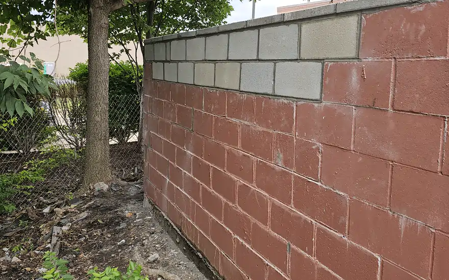 A block garden wall finished with a run of cut stone cap, following the line of the yard.
